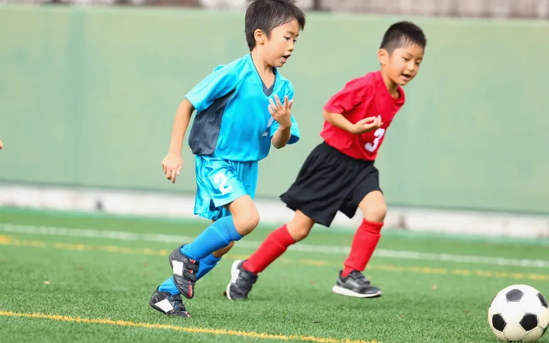 サッカーの試合でボールを追う子どもたち