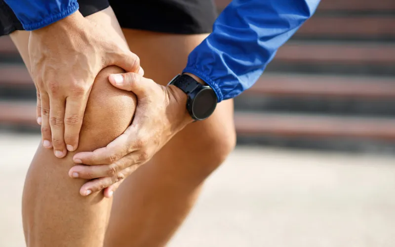 運動中に膝の痛みを感じて患部を押さえる様子