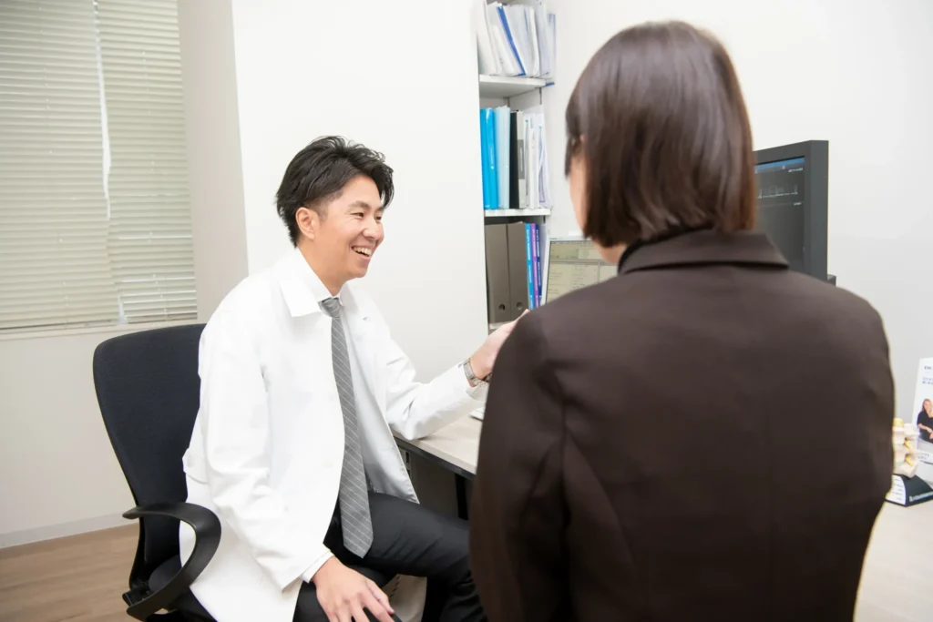 診察室で患者さんの話を聞く医師