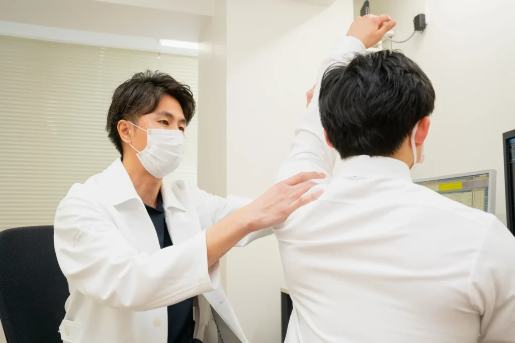 診察室で患者さんの肩の動きを確認する医師