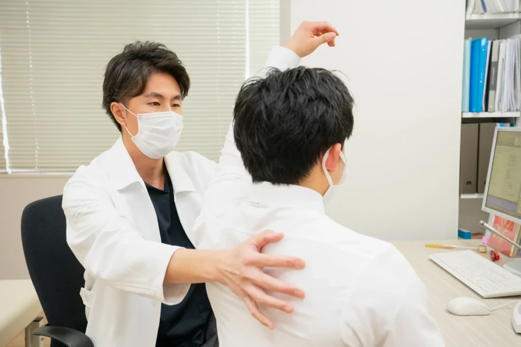 診察室で患者さんの背中に触れて診察する医師