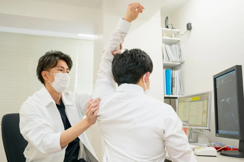 診察室で患者さんの腕の可動域を確認する医師