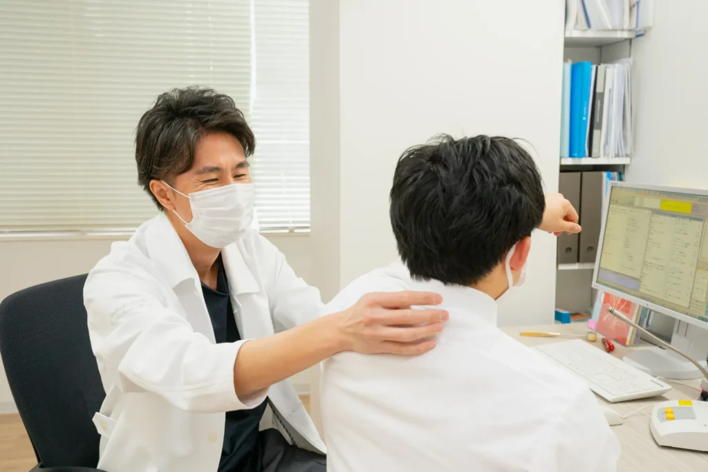診察室で患者さんの肩や背中の状態を確認する医師